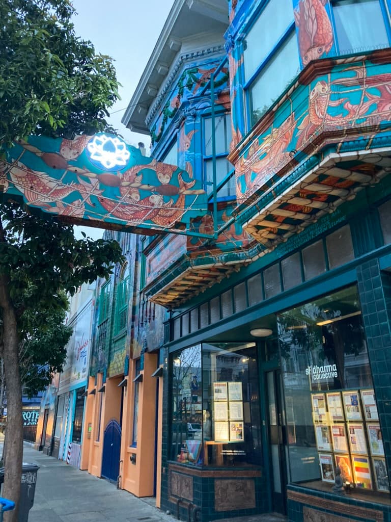 San Francisco Dharma Collective's storefront lit up at dusk, with its glowing lotus sign